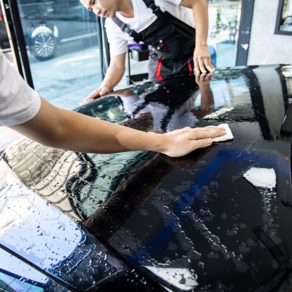 Technician installs car paint protection film. Technician with transparent film, car paint protection. Technician installs car paint protection film. Install car paint protection film. Car wrap concept.